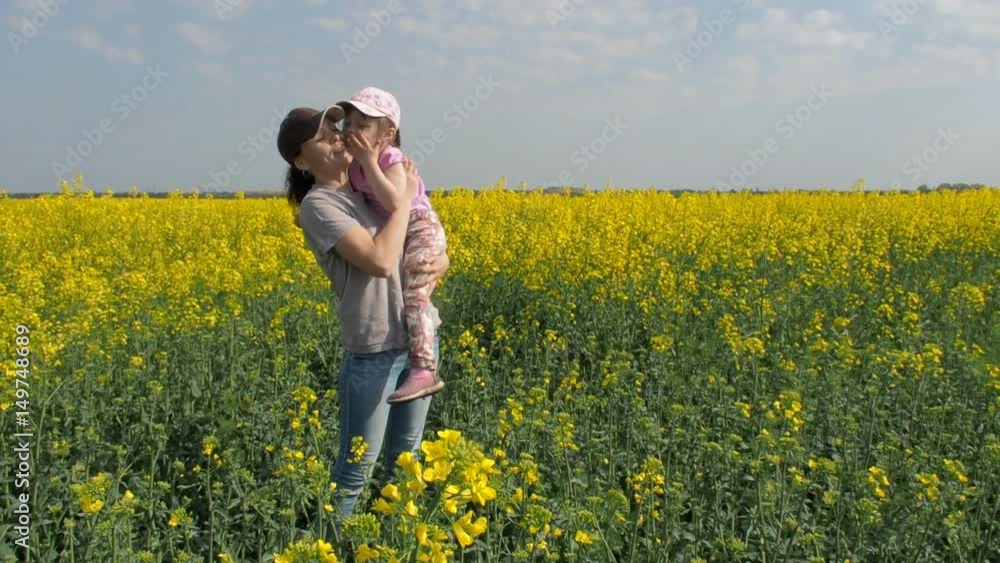 Mother hugging her daughter in nature. Woman with little girl on yellow field. A happy family. Rapeseed field. Mother hugging her daughter in nature. Woman with little girl on yellow field. A happy family. Rapeseed field.