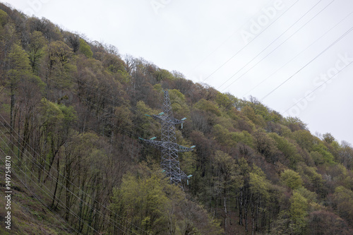 Tower of high-voltage power lines on forest background