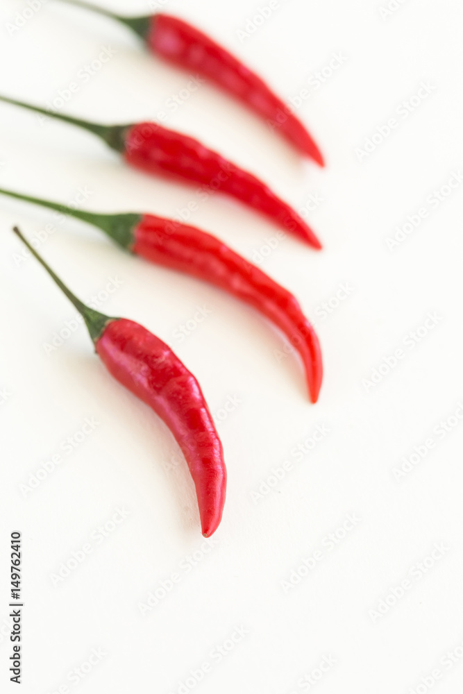 red hot chili peppers, popular spices concept - closeup on four delicious juicy clean pod of red hot chili peppers with green stalk isolated on white background, selective focus, free space for text red hot chili peppers, popular spices concept - closeup on four delicious juicy clean pod of red hot chili peppers with green stalk isolated on white background, selective focus, free space for text