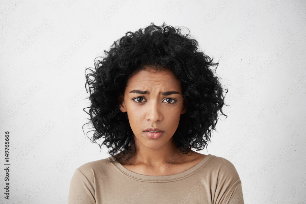 Beautiful young dark-skinned woman wearing beige top frowning looking at camera, having clueless facial expression, feeling confused about talk with her boyfriend. Life perception and attitude Beautiful young dark-skinned woman wearing beige top frowning looking at camera, having clueless facial expression, feeling confused about talk with her boyfriend. Life perception and attitude