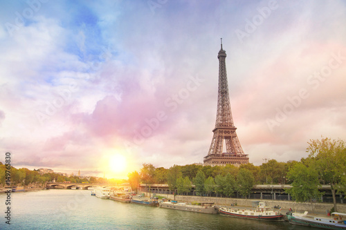 Eiffel tower sunset with clouds. Romantic sunset background. Old Monument with boats on Seine river in Paris, France.