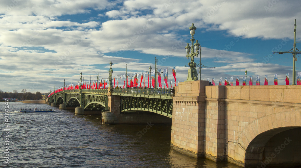 Trinity bridge in May with Victory day decorations above Neva river with pleasure boat. Blue sky with clouds. Saint Petersburg, Russia.
