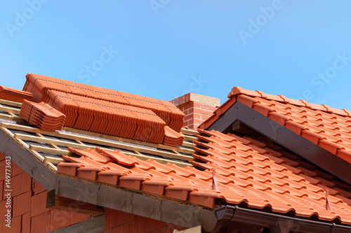 roof under construction with stacks of red ceramic roof tiles ready to fasten photo