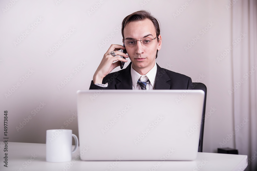 Young business man drinking coffee and talking on a cell phone in the office
Young business man drinking coffee and talking on a cell phone in the office