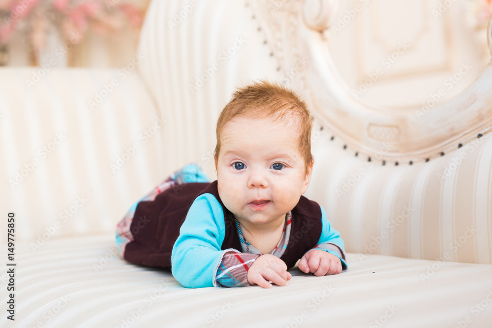 Close-up portrait of baby boy with red hair and blue eyes. Newborn child lyling in couch. Close-up portrait of baby boy with red hair and blue eyes. Newborn child lyling in couch.