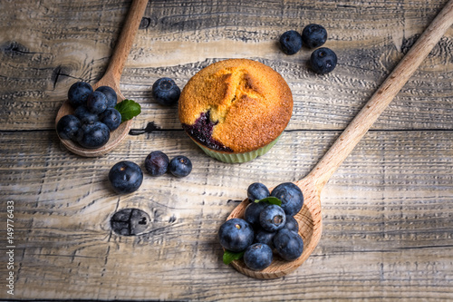 Fototapeta Naklejka Na Ścianę i Meble -  Blueberry muffin and blueberries on a wooden spoon on wooden background