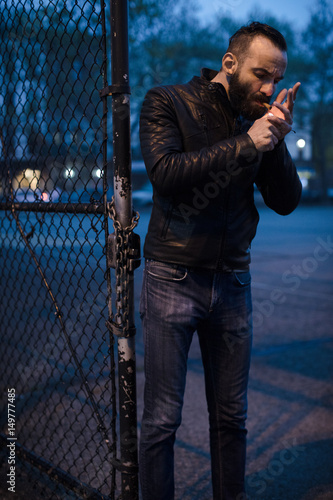 A middle aged, Arabic man lights a cigar in the streets of Brooklyn, New York City. Shot using ambient lighting during the sping of 2017.