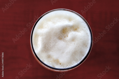 Glass of beer foam over wooden table