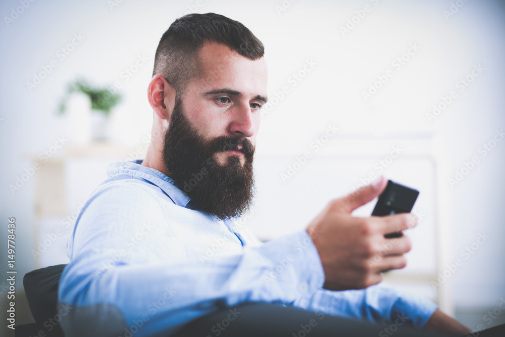 Young businessman sitting on chair in office with phone Young businessman sitting on chair in office with phone