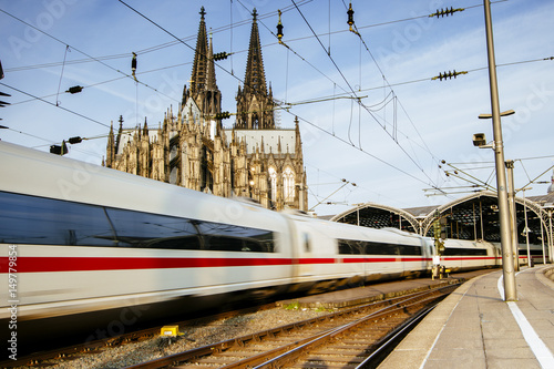 Zug fährt durch Kölner Bahnhof mit Dom im Hintergrund