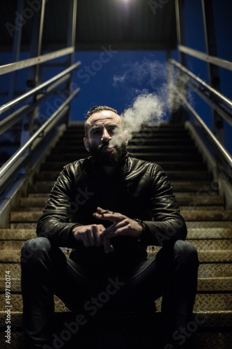 A closeup portrait of a middle aged, Egyptian man smoking alone in the streets of Brooklyn, New York. Shot using ambient light during the spring of 2017.