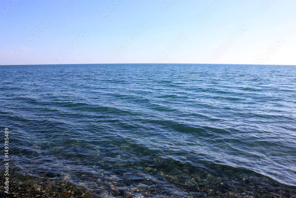 Stony shore of serene blue sea.