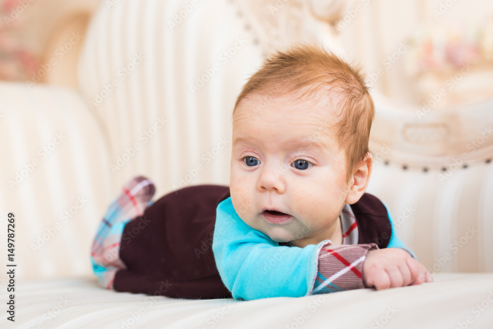 Adorable baby boy in sunny bedroom. Newborn child relaxing on the couch. New born kid during tummy time. Adorable baby boy in sunny bedroom. Newborn child relaxing on the couch. New born kid during tummy time.