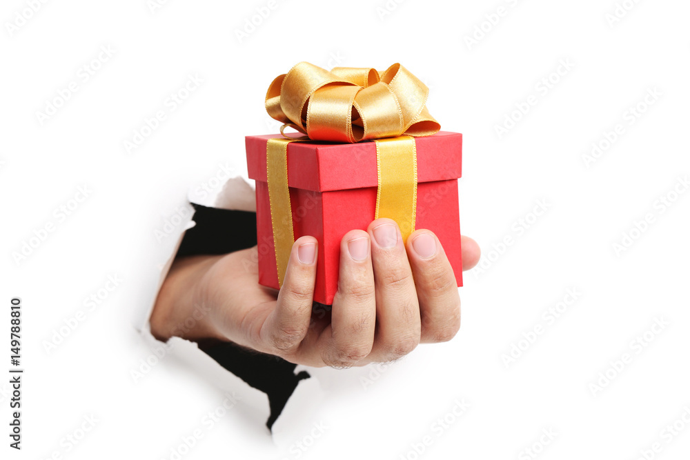 Male hand with gift box punching through the paper Male hand with gift box punching through the paper