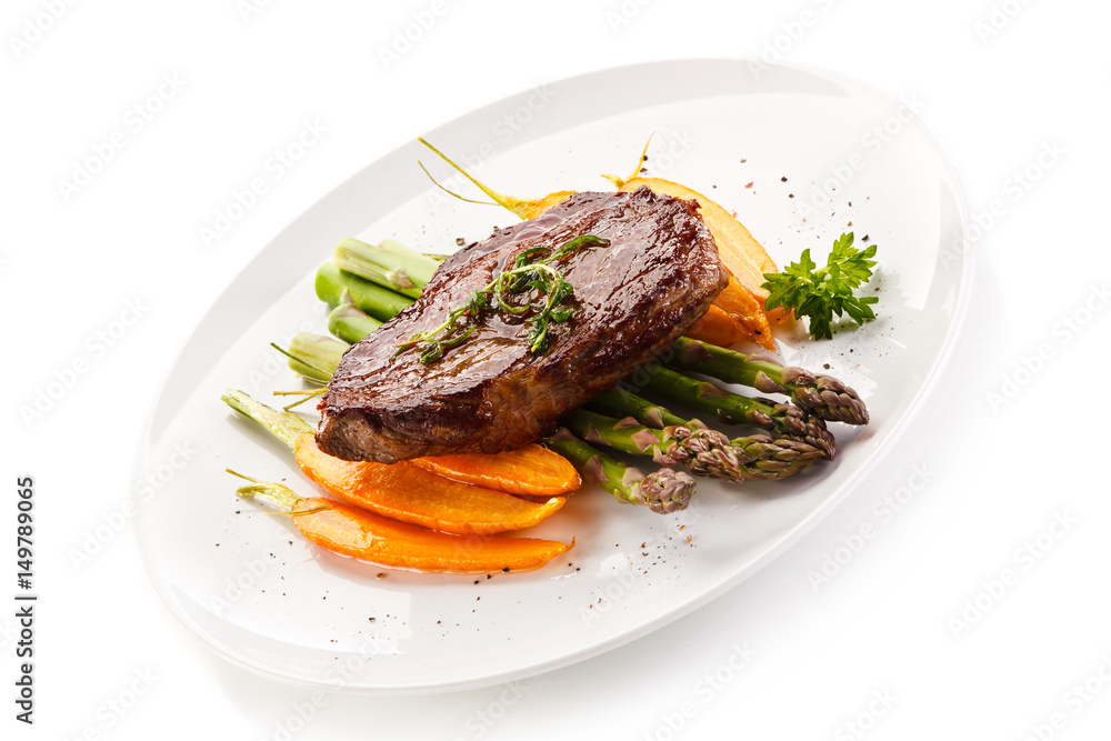 Grilled beefsteak with asparagus and carrot on white background Grilled beefsteak with asparagus and carrot on white background