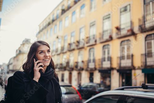 Smiling young woman talking wit her friend with her smartphone on the street.Communicating with friends,free calls and messages for young people.Cheerful casual business woman talking on her phone © eldarnurkovic