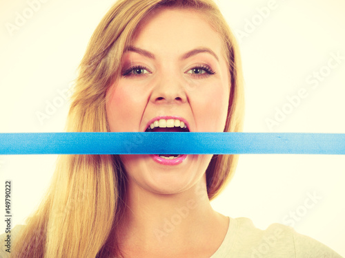 Tableau sur toile Attractive blonde woman biting tape on mouth.