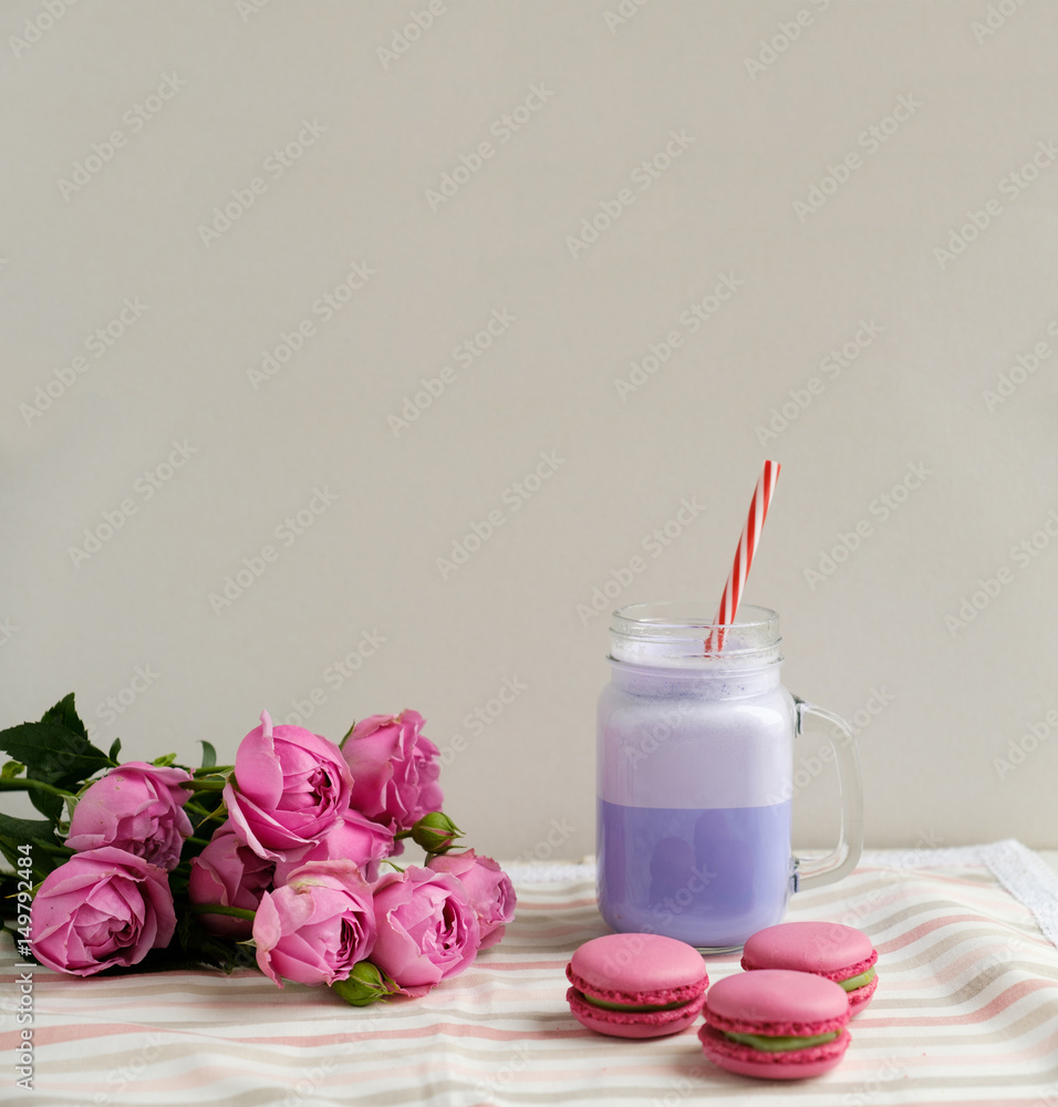 Purple coffee in stylized mason jar cup with macarons and roses and colorful decoration. Blueberry milk shake. Unicorn coffee. Unicorn food Purple coffee in stylized mason jar cup with macarons and roses and colorful decoration. Blueberry milk shake. Unicorn coffee. Unicorn food