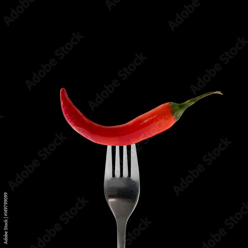 Red hot chili pepper on fork, isolated on black © htpix