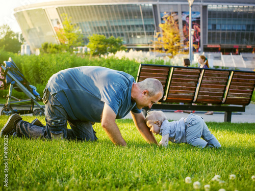 A man and a baby crawling on grass