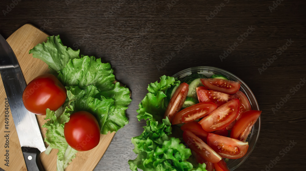 tomato and cut tomato, cucumber and a kitchen knife on a cutting board tomato and cut tomato, cucumber and a kitchen knife on a cutting board