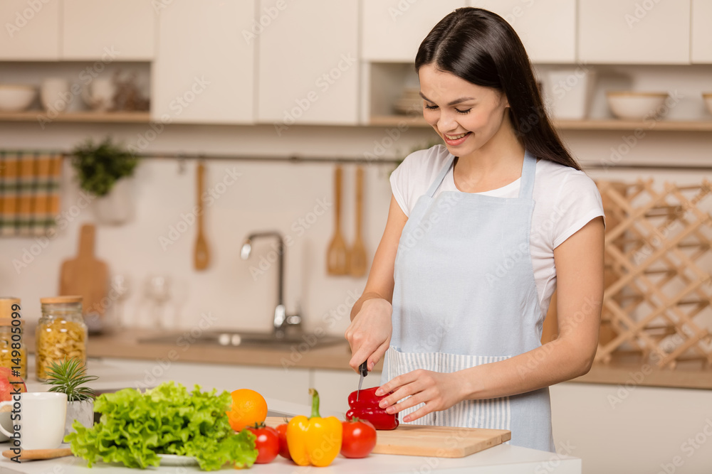 Cooking young woman in kitchen. Food blogger concept. Smiling.