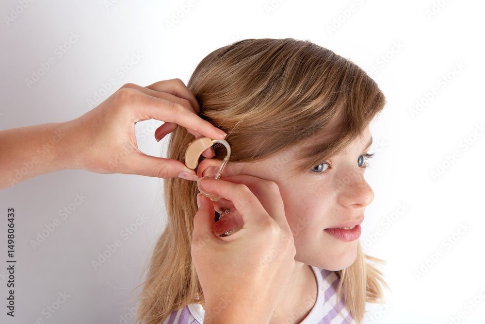 Doctor fitting a young girl patient with hearing aid Doctor fitting a young girl patient with hearing aid