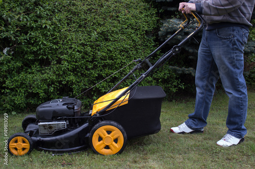 A man mows the grass with a gasoline mower