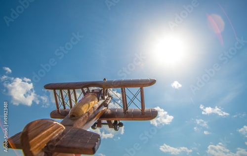 The wooden plane fly on the background of a bright sun