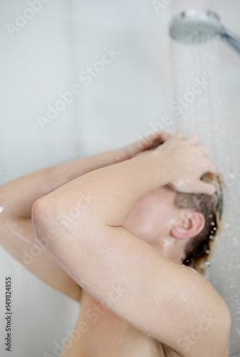 Beautiful naked woman washing her hair while taking shower.