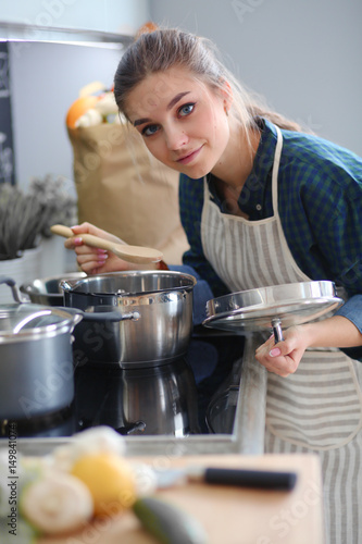Young woman cooking in her kitchen standing near stove