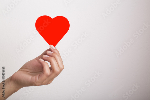 Hand holding a paper heart on white background