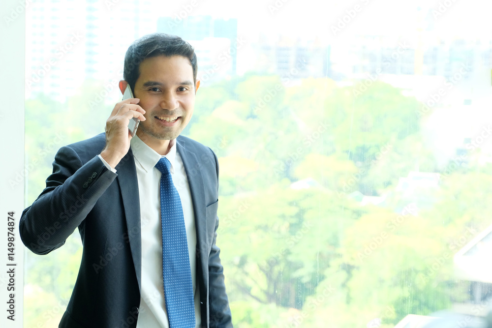 Business man talking smart phone by windows with city view, inside office building background, businessman on phone Business man talking smart phone by windows with city view, inside office building background, businessman on phone