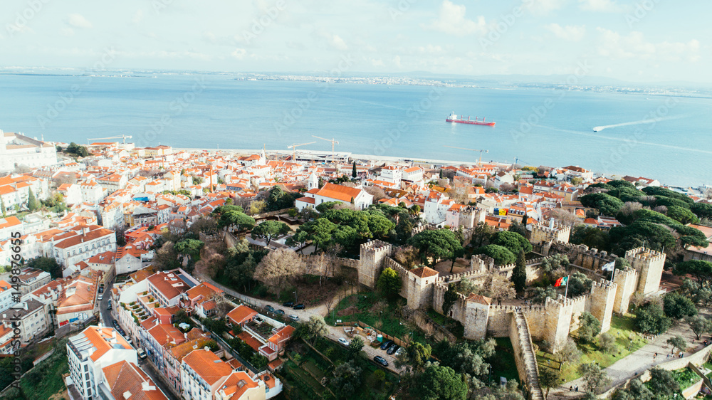 Fototapeta premium Aerial panoramic view over Lisbon in beautiful sunset sunshine.Saint George castle,downtown and neighbourhood of Alfama,river Tagus in european capital,Lisbon,Portugal.Aerial travel photography 