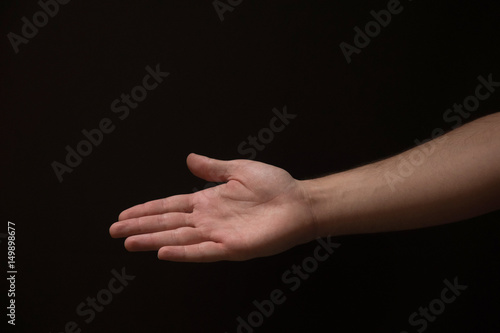 Open male hand coming out of the right side of the frame, on a black background
