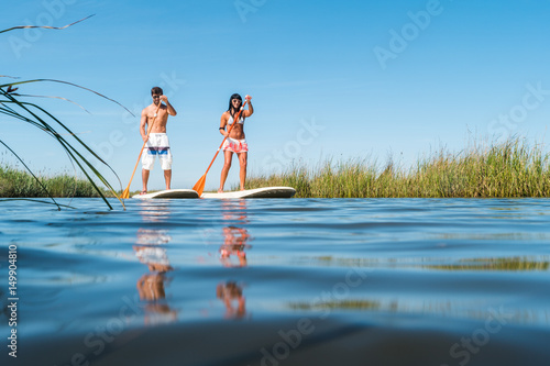 Obraz na płótnie Man and woman stand up paddleboarding