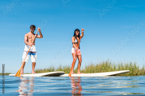 Man and woman stand up paddleboarding photo