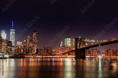 Brooklyn Bridge in the evening with midnight blue sky and smooth water surface shot from Brooklyn side