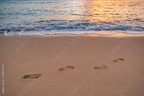 Footprints on wet sand of shoreline at a beach after ocean water has gone. Sunset time golden light beautiful pinky tone