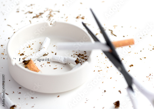 Wallpaper Mural white ashtray with destroyed cigarette that emphasize words "i quit" from complete quote "i will quit tomorrow", blurred black blade scissors cutting cigarette as forground Torontodigital.ca
