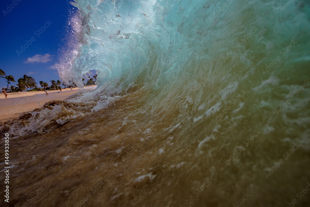 Shorebreak Ocean Wave in a shape of rip curl barrel, ready to crush against sand on a tropical beach. Hawaiian lifestyle