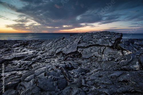 Canvas Print Black scenery of Lava fields, lava rock against sunset ocean at Hawaii