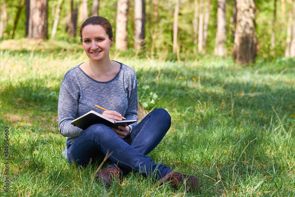 beautiful young girl in nature, making notes in a notebook beautiful young girl in nature, making notes in a notebook