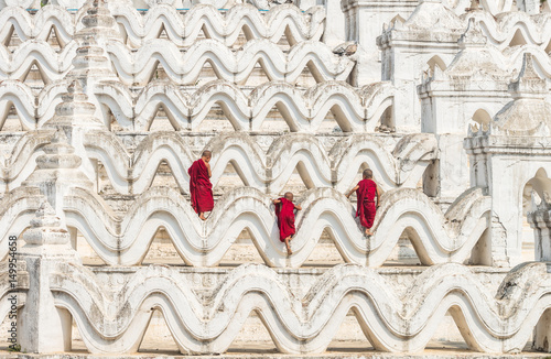 Photography Back side of three young monk are Climbing up on the Mya Thein Tan Pagoda at bag