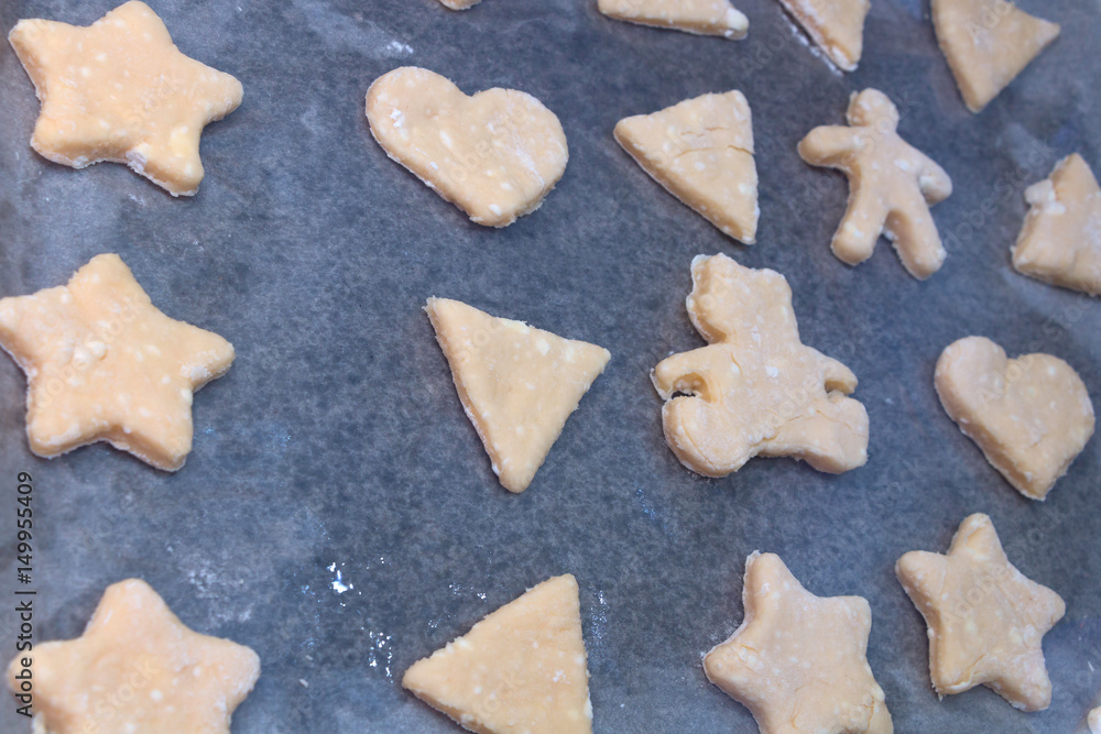 Cookie dough in different shapes lies on the baking sheet.