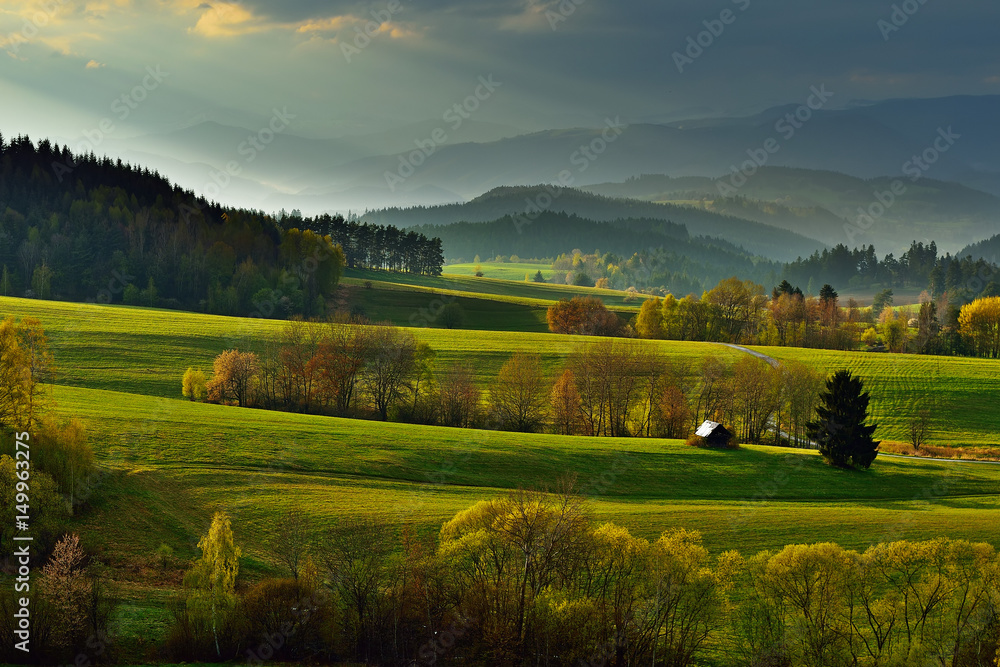Spring forest and meadows landscape in Slovakia. Coming storm panorama. Blooming cherry trees. Sunlit country.