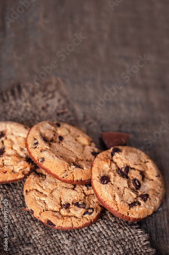 Chocolate cookies on dark  napkin on wooden table. Chocolate chip cookies on brown coffee color cloth, macro, top view