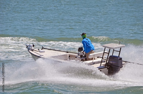 Small sport fishing skiff powered by a single outboard engine speeding on the florida intra-coastal waterway .