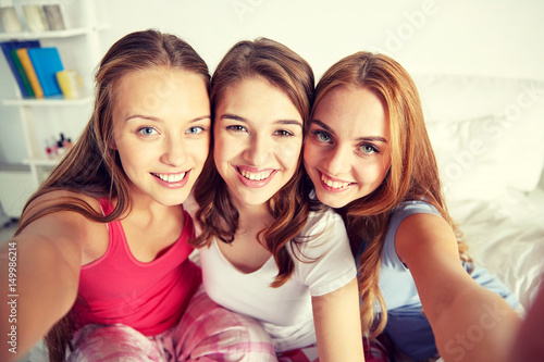 happy friends or teen girls taking selfie at home