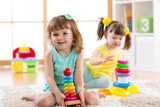 Children playing together. Educational toys for preschool and kindergarten kids. Little girls build pyramid toys at home or daycare.